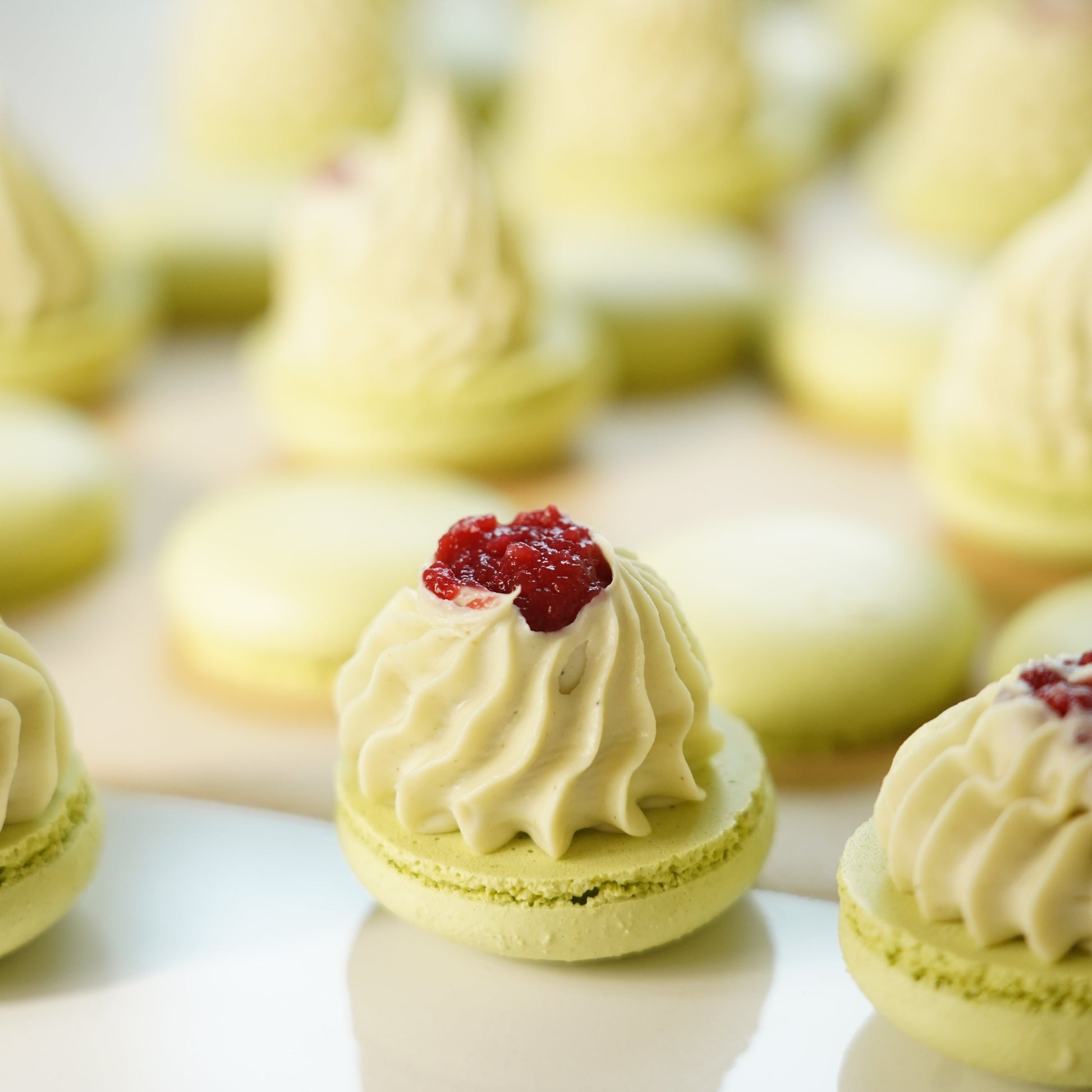 Macarons with white filling and a red berry on a white background