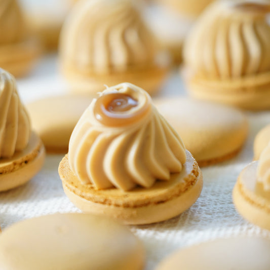 Close-up of macarons with intricate caramel designs on a white surface